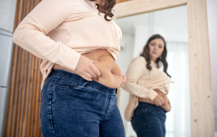 Mulher medindo cintura: controle de peso e prevenção da obesidade pós-menopausa.