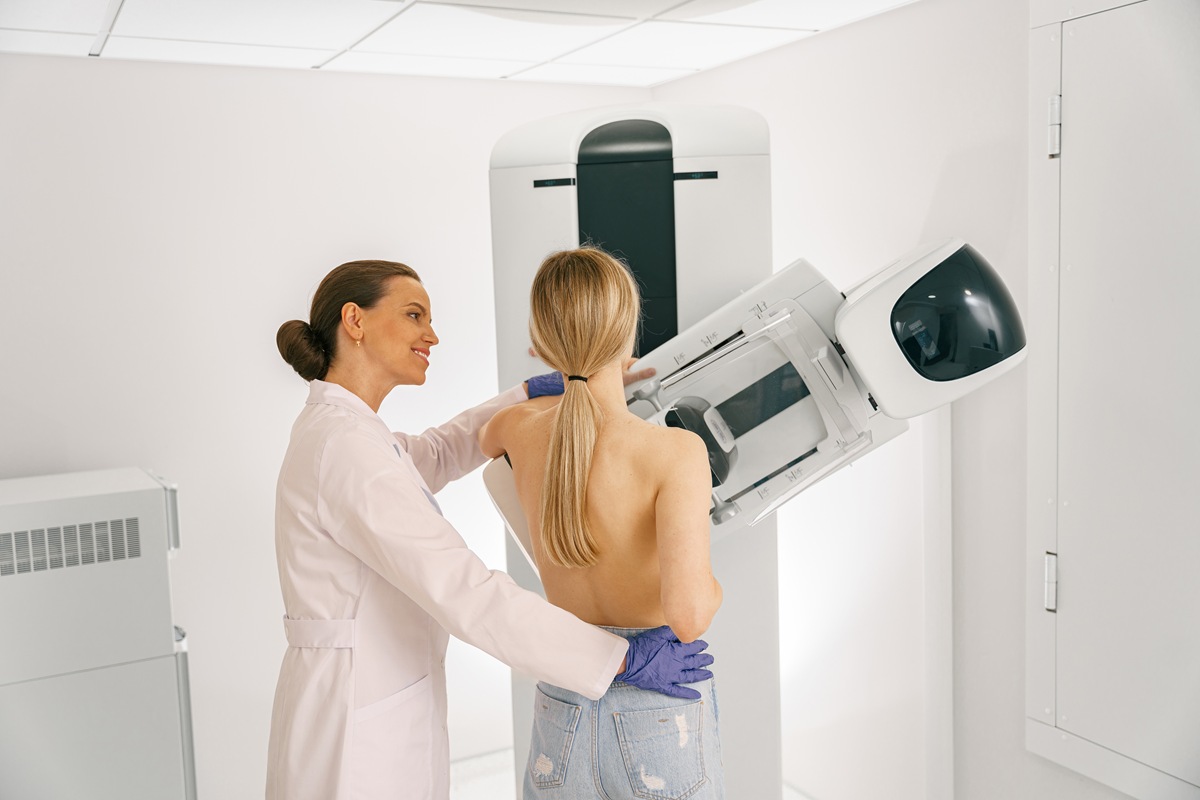Mulher realizando exame de mamografia em equipamento moderno, com compressão mamária segura para imagens precisas.
