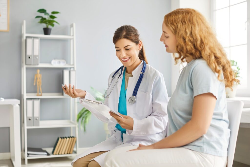Médica e paciente em conversa durante consulta, trocando olhar de compreensão e confiança.