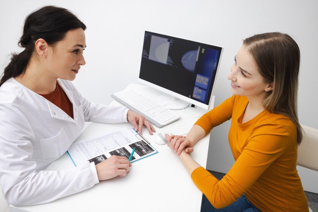 Médica e paciente analisando exame de mamografia juntas durante consulta de mastologia.